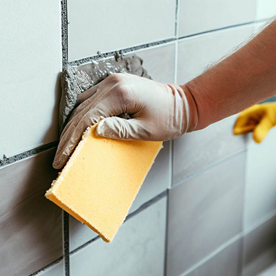 Man grouting tiles using a grout float